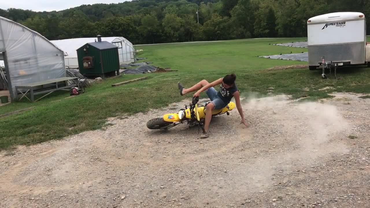 Woman on yellow dirt bike spins and falls