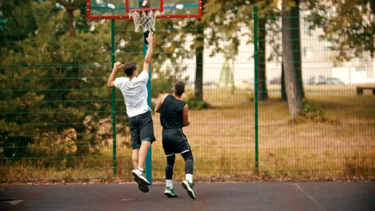 Pair of young men playing basketball in a park