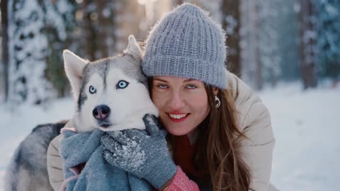 a beautiful girl playing with a dog in the snow