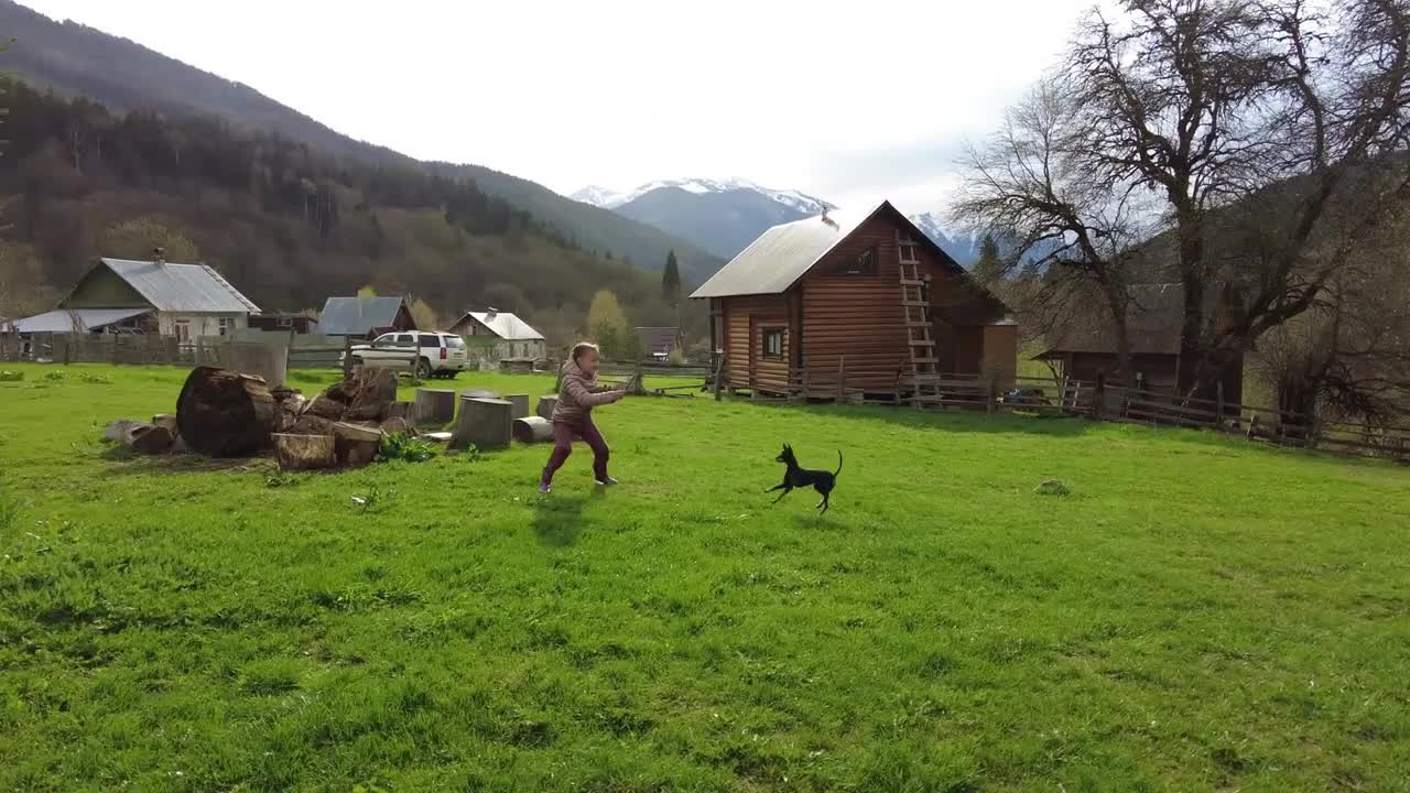 Child girl is playing with the dog outdoor at countryside