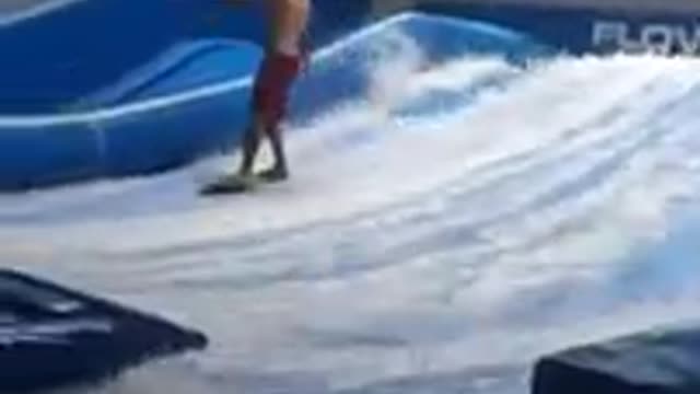 Red shorts kid surfing inside and falls onto blue barrier