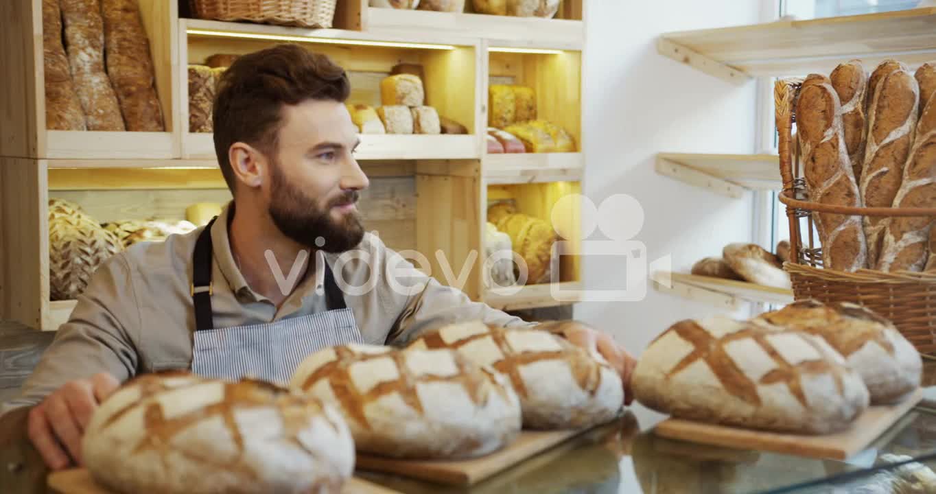 The Male Vendor In The Bakery Shop Bringing Just Baked Bread To The Counter