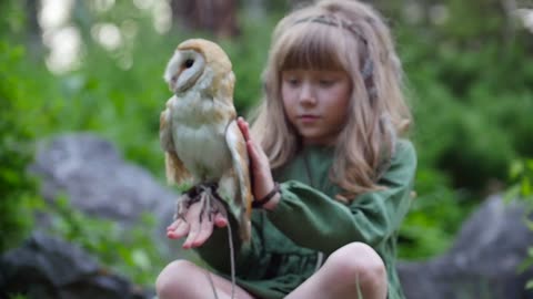 Little girl with an owl in a fairy forest. Friends