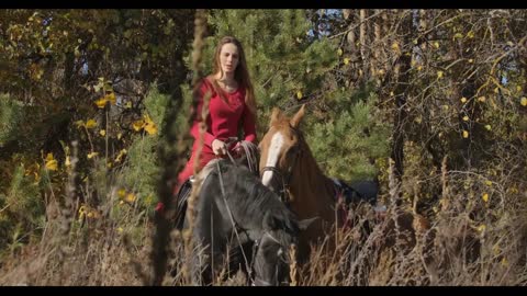 Portrait of young Caucasian female equestrian sitting on back of black horse and holding halter