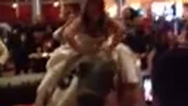 Bride rides mechanical bull in wedding gown