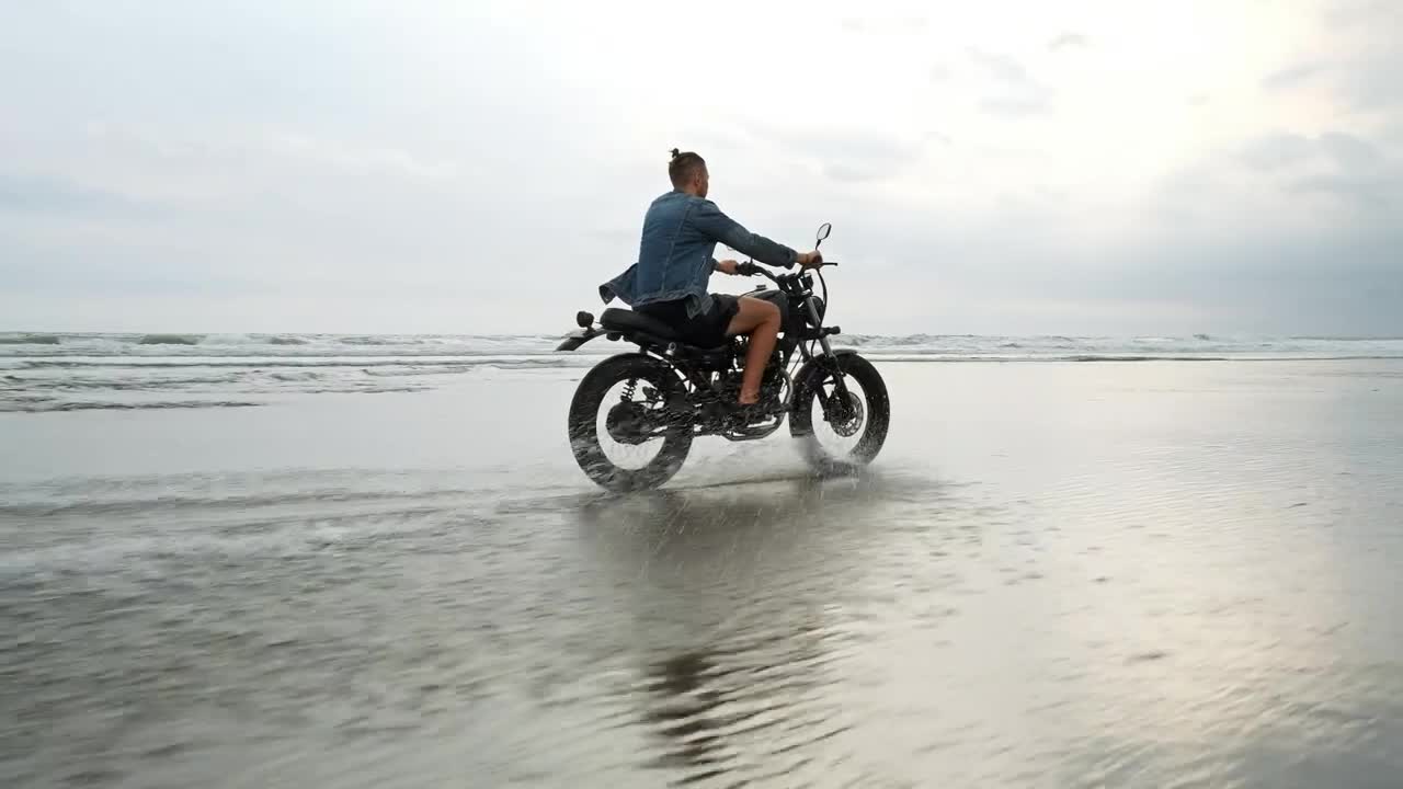 Hipster biker riding a motorcycle near the seashore