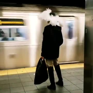 Woman wears a large feather hat at subway station