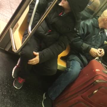 Man with red luggage clips his fingernails on subway train