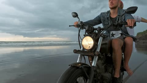 Man with his girlfriend riding motorcycle on beach