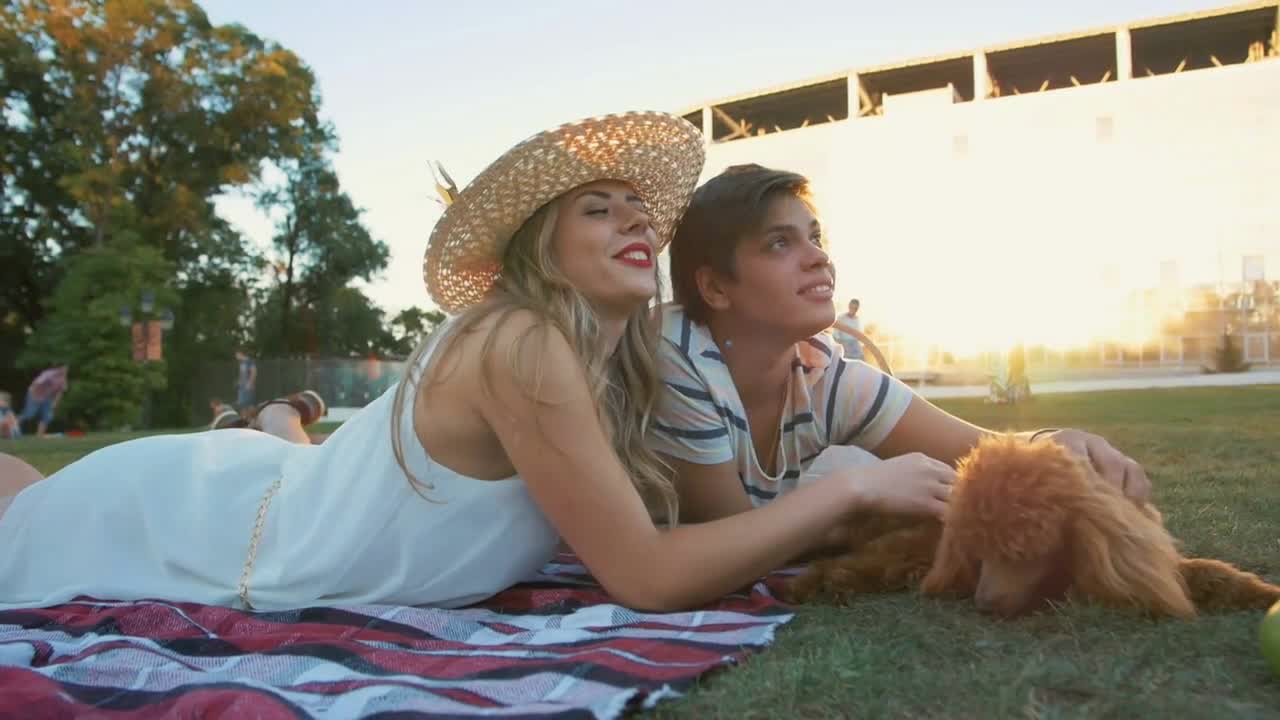 Happy young couple on picnic resting playing with dog and rabbit