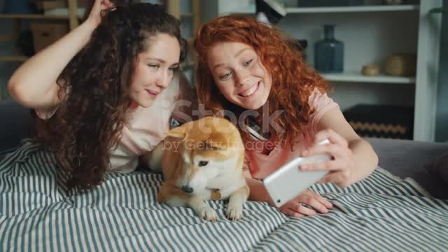 Pretty Girls Taking Selfie With Cute Dog Using Smartphone On Couch Together