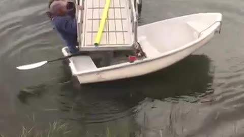 Blue sweater struggles to get white boat under dock