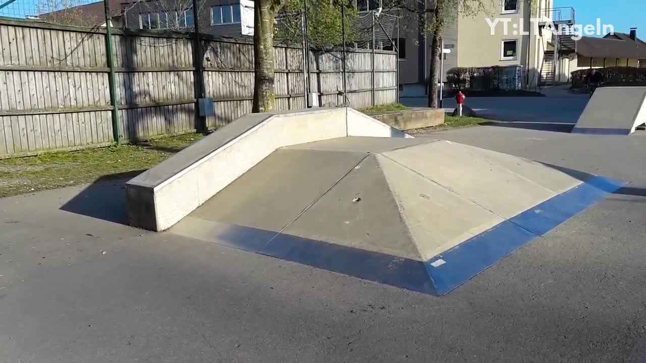 Blue helmet bicycle guy jumps skate park hill falls down