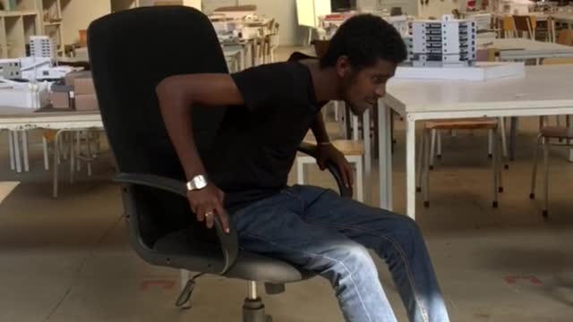 Guy in jeans leans back in office chair and falls