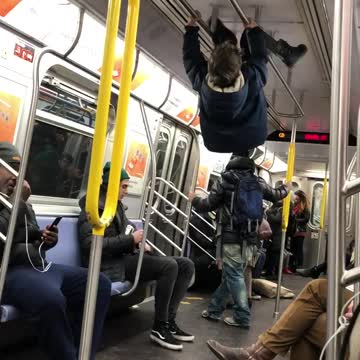 Little boy climbs ceiling handrails and hangs upside down in subway train