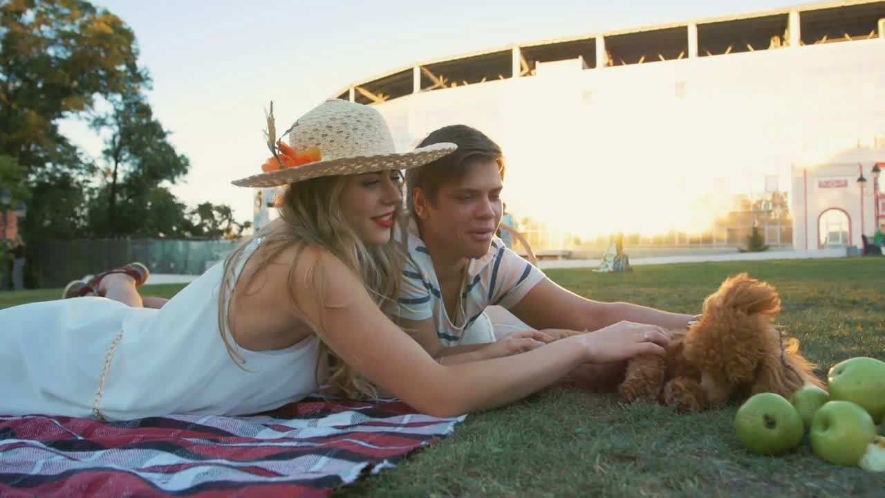 Happy young couple on picnic resting playing with dog and rabbit