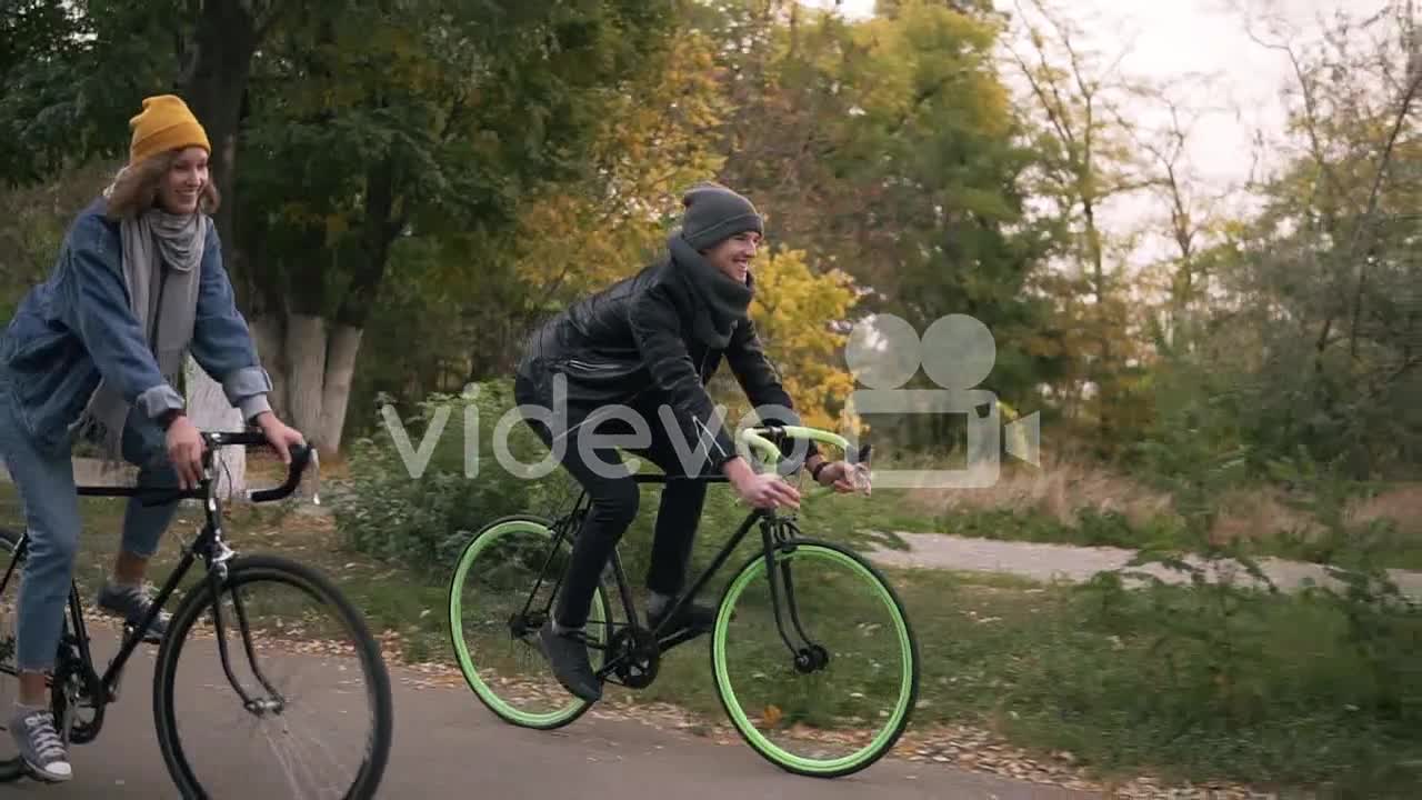 Young Hipster Couple Enjoying Cycling Through Park On Trekking Bikes