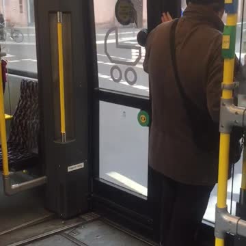 Black beanie brown jacket dancing bus door headphones