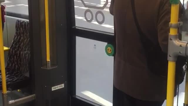 Black beanie brown jacket dancing bus door headphones