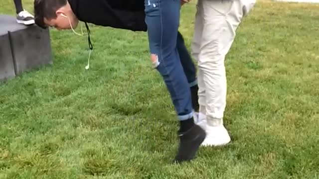 Slow mo blue jeans kid has hands pulled between legs faceplants