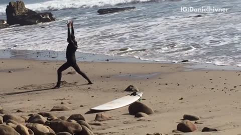 Guy filmed doing karate poses next to board on beach