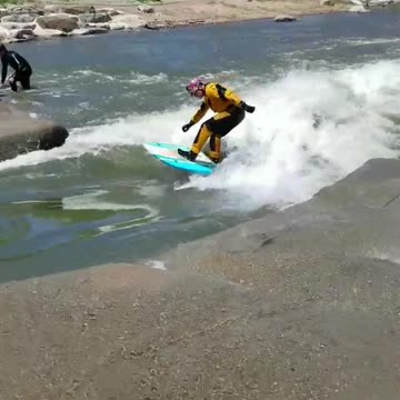 Guy yellow suit river surfing
