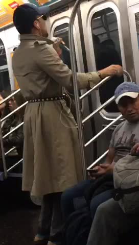 Man in brown trench coat dancing on subway