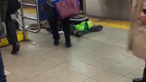 Man in red sits next to outlet on subway platform