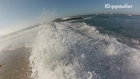 Slo mo wave crashes into surfer on concrete