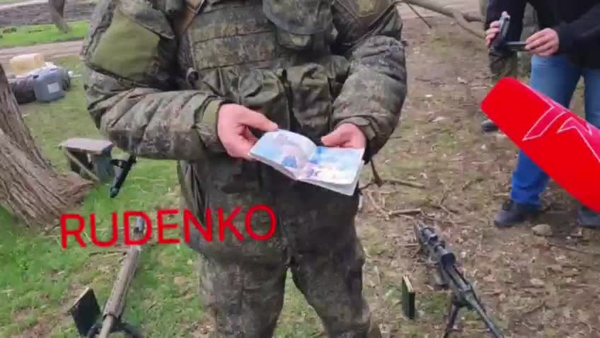 A Russian soldier shows the passport of a killed US mercenary * See Description*
