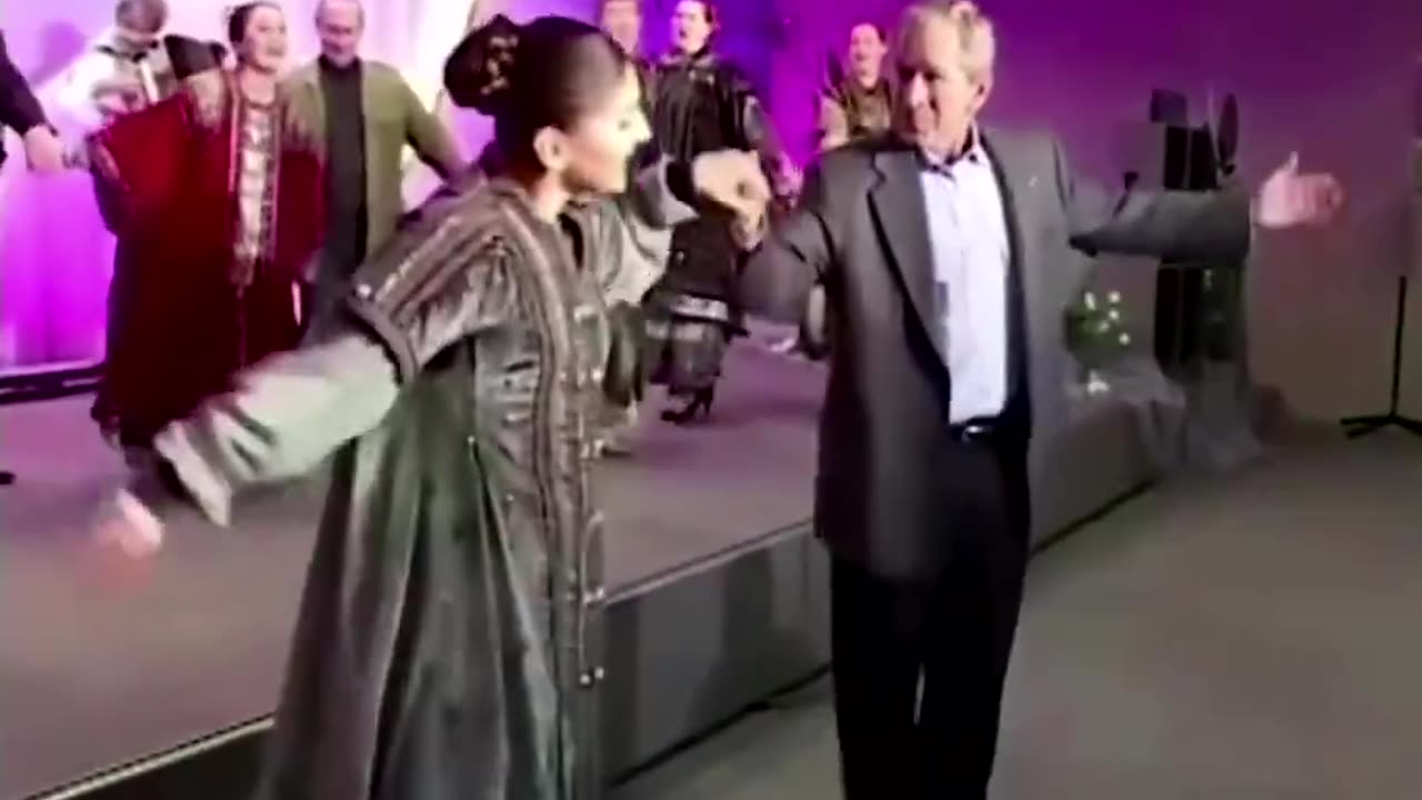 George W. Bush dancing to a Russian folk song with Vladimir Putin in the background