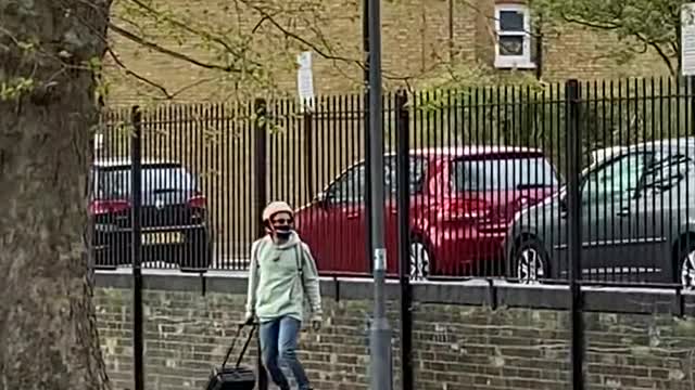 Guy Riding on Hoverboard Crosses the Street While Carrying his Suitcase