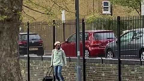 Guy Riding on Hoverboard Crosses the Street While Carrying his Suitcase