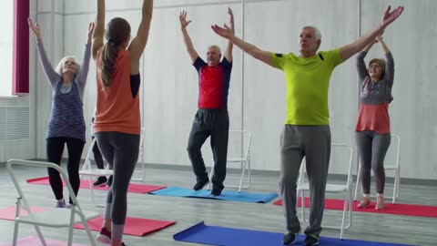 A Woman Fitness Instructor Teaching The Group Of Elderly People Some Exercises Fitted For Them