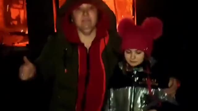 A woman and her daughter stand in front of their burning home, saying Thank you Putin