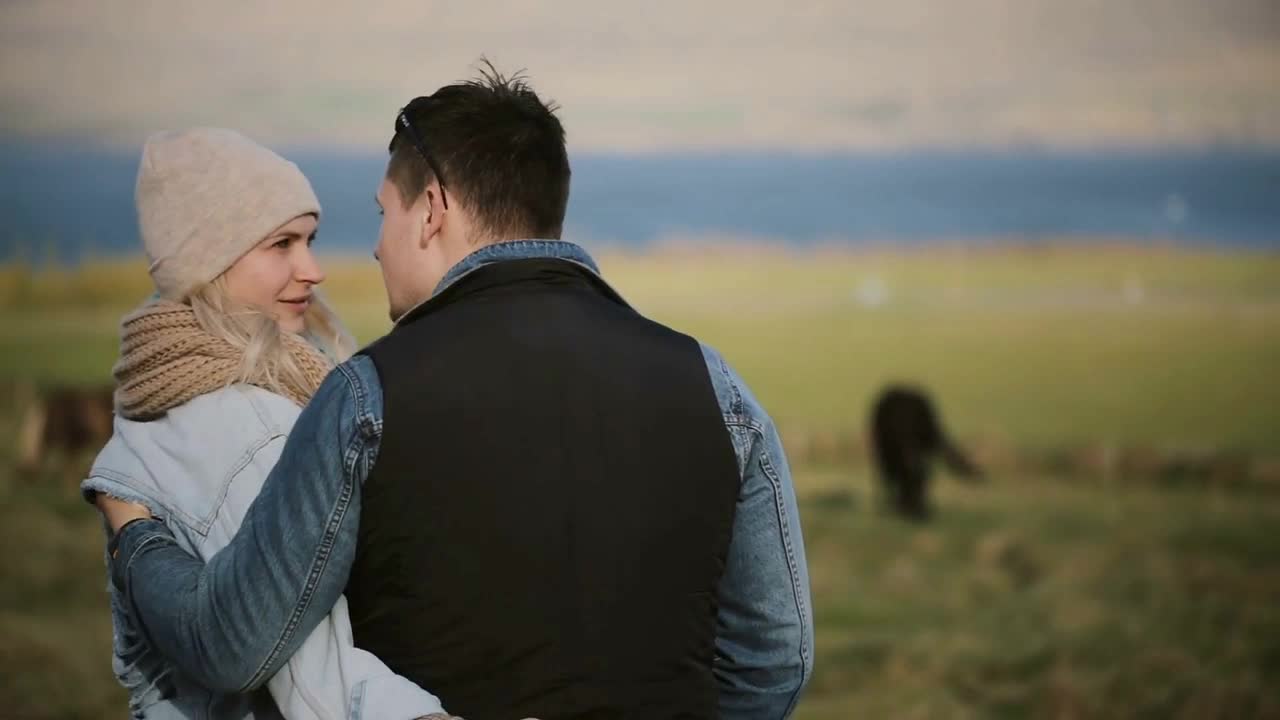 Back view of young couple standing on the field and enjoying the landscape