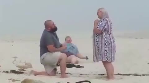 Fat woman trips on beach and falls in sand