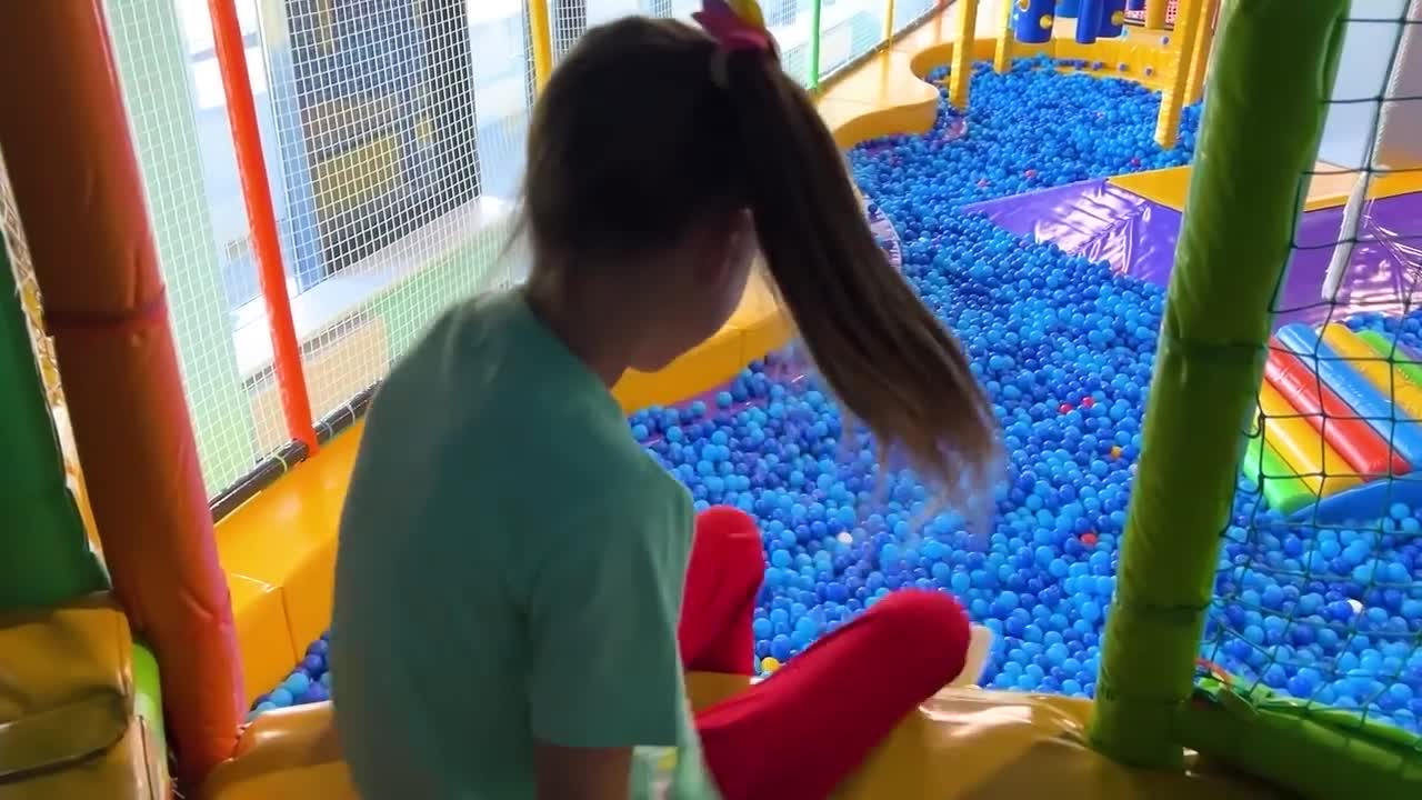 Sofia and a lot of colored balls on the Playground for kids