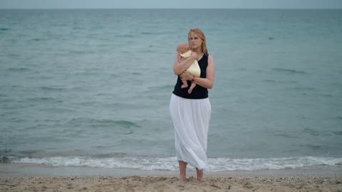 Mother holding her baby alone at the shore