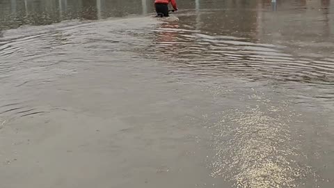 Cyclist Attempts to Ride Through Flooded Parking Lot