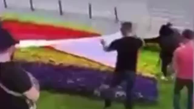 Polish activists getting rid of the Ukrainian symbols covering a flower bed with the flag of Poland