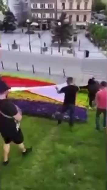 Polish activists getting rid of the Ukrainian symbols covering a flower bed with the flag of Poland
