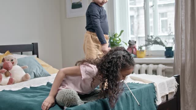 kids-playing-catch-the-bait-with-their-cat-in-the-bedroom