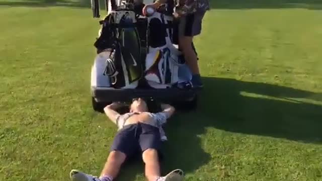 Guy is dragged by golf cart while beer poored into mouth and then hit by following golf cart