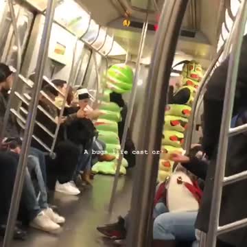 Two people dressed as green caterpillars on subway