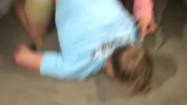 Blonde man i blue shirt faceplant backflip in sand