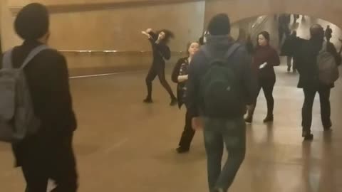 Woman in black outfit dancing in train station