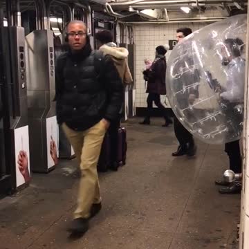 Man in clear inflatable bubble trying to get to subway