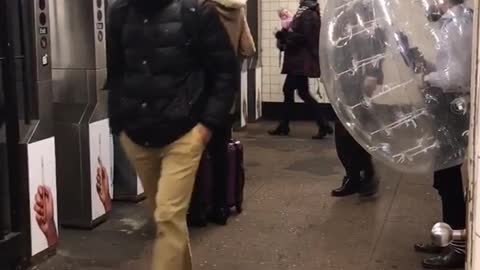 Man in clear inflatable bubble trying to get to subway