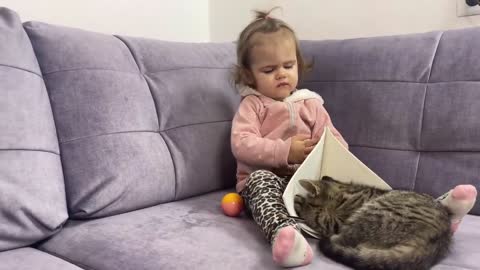 A kitten interrupts a cute baby while she is drawing